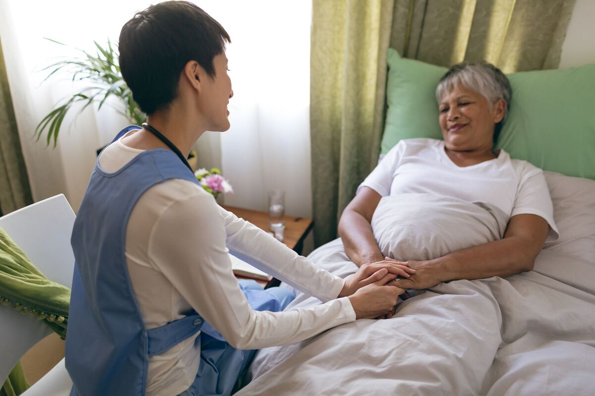 nurse caretaker comforting elderly patient