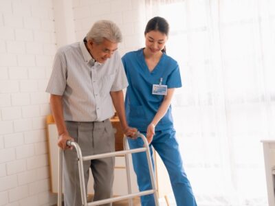 A nurse helping an old person with a walker