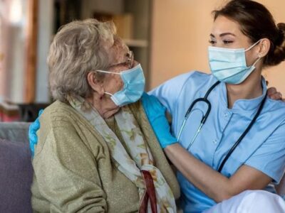 A nurse touching an old person's face.